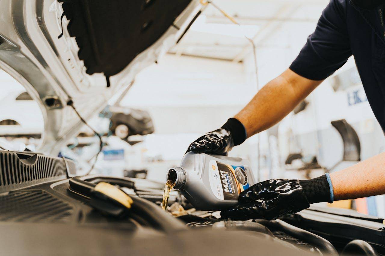 Meccanico che verifica il livello dell'olio motore con l'astina durante un controllo in officina