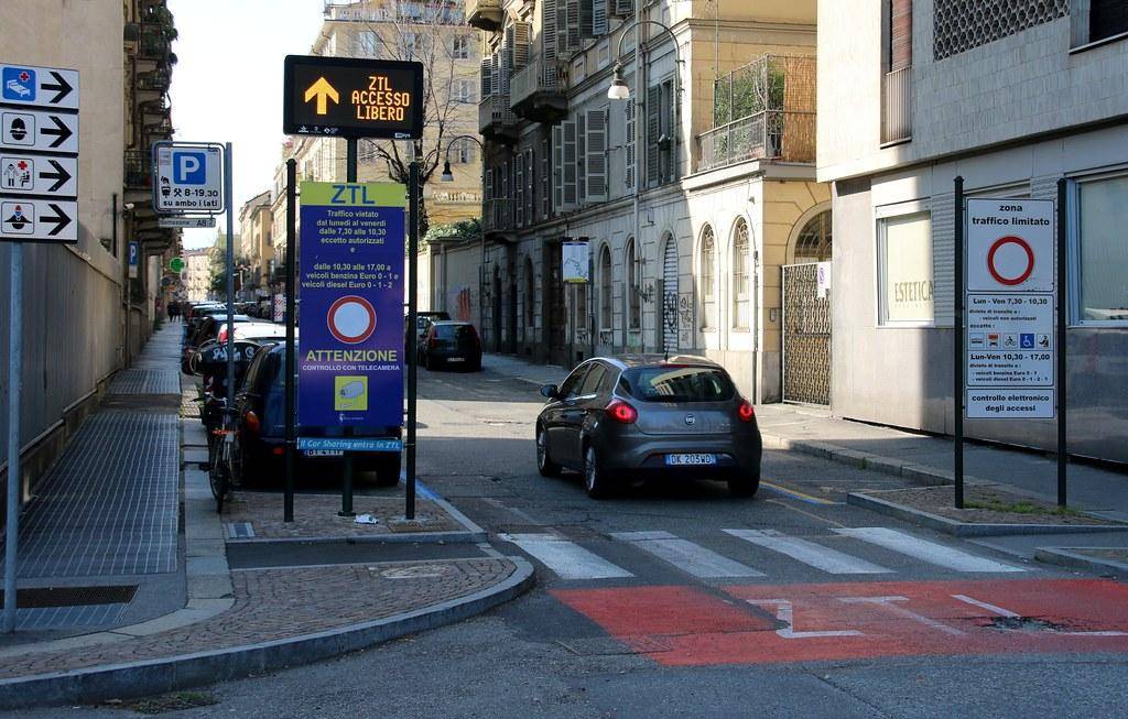 Segnale verticale di ingresso ZTL con telecamera di controllo e display luminoso varco attivo in una strada del centro storico italiano