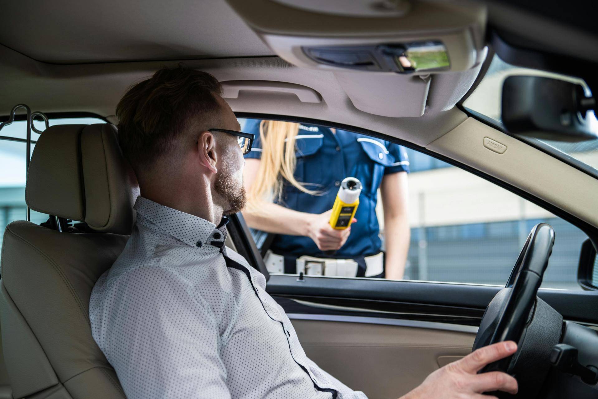 Agente di polizia stradale che sottopone un automobilista all'etilometro durante un controllo