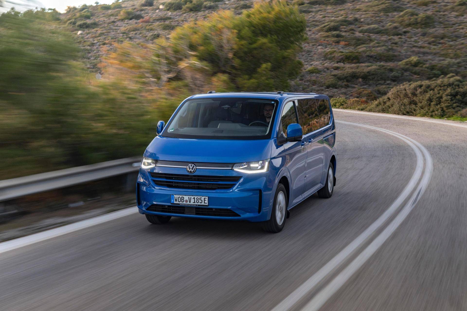 Volkswagen Caravelle auto a 9 posti blu che viaggia su strada